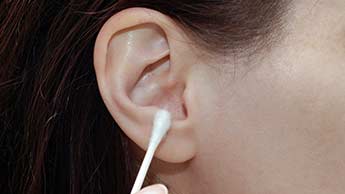 osoba czyszcząca uszy za pomocą patyczka higienicznego