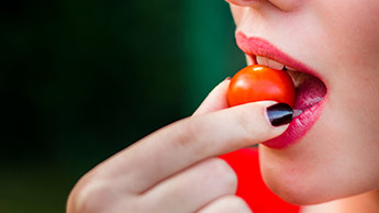 Mulher comendo um tomate-cereja